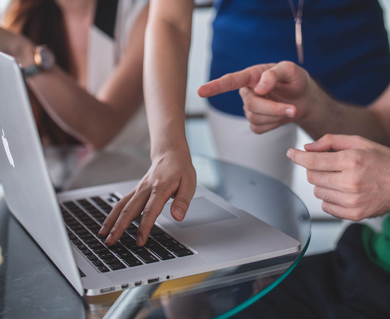 laptop with two people collaborating